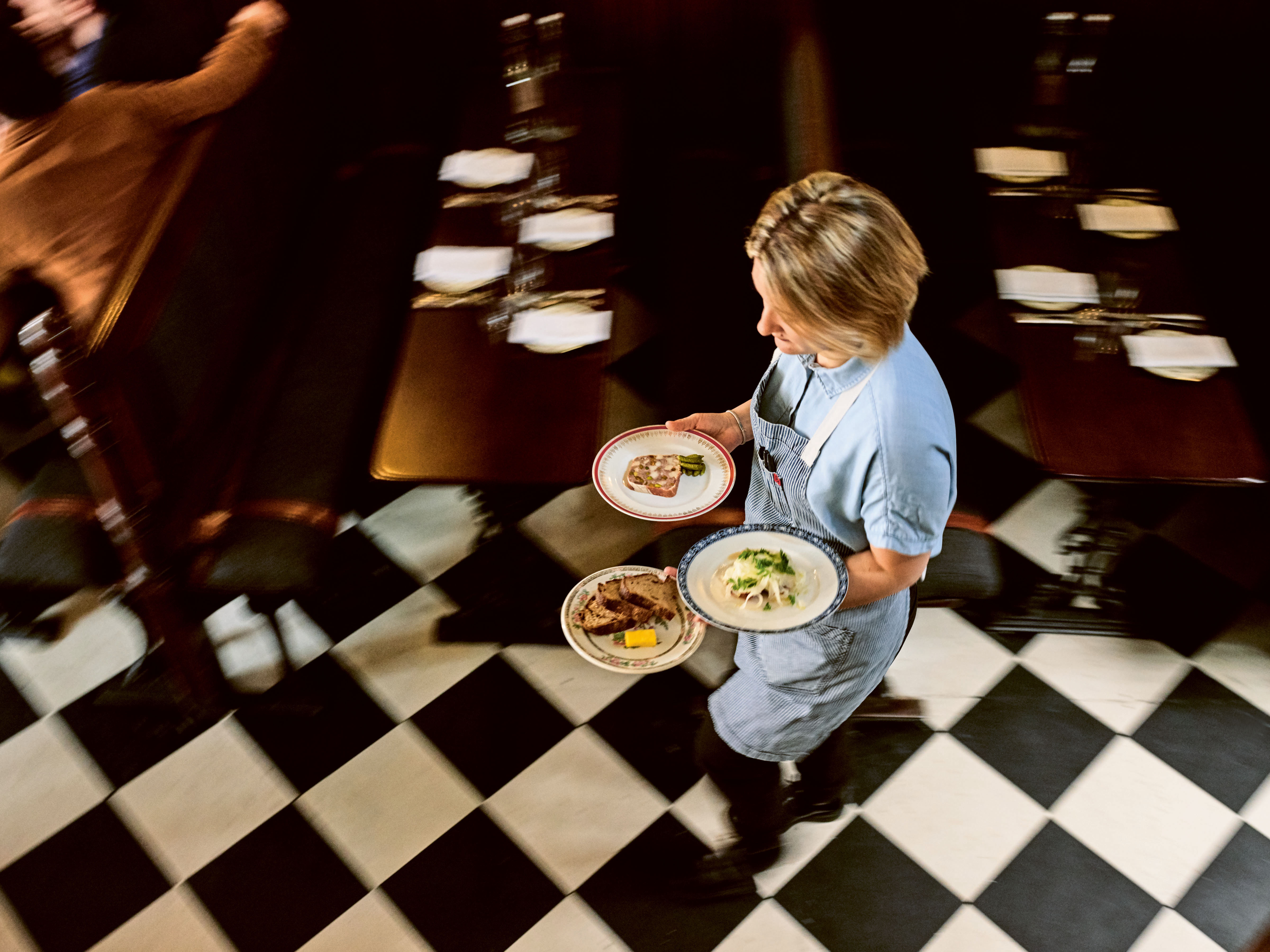 Waitress carrying plates of food in a restaurant.