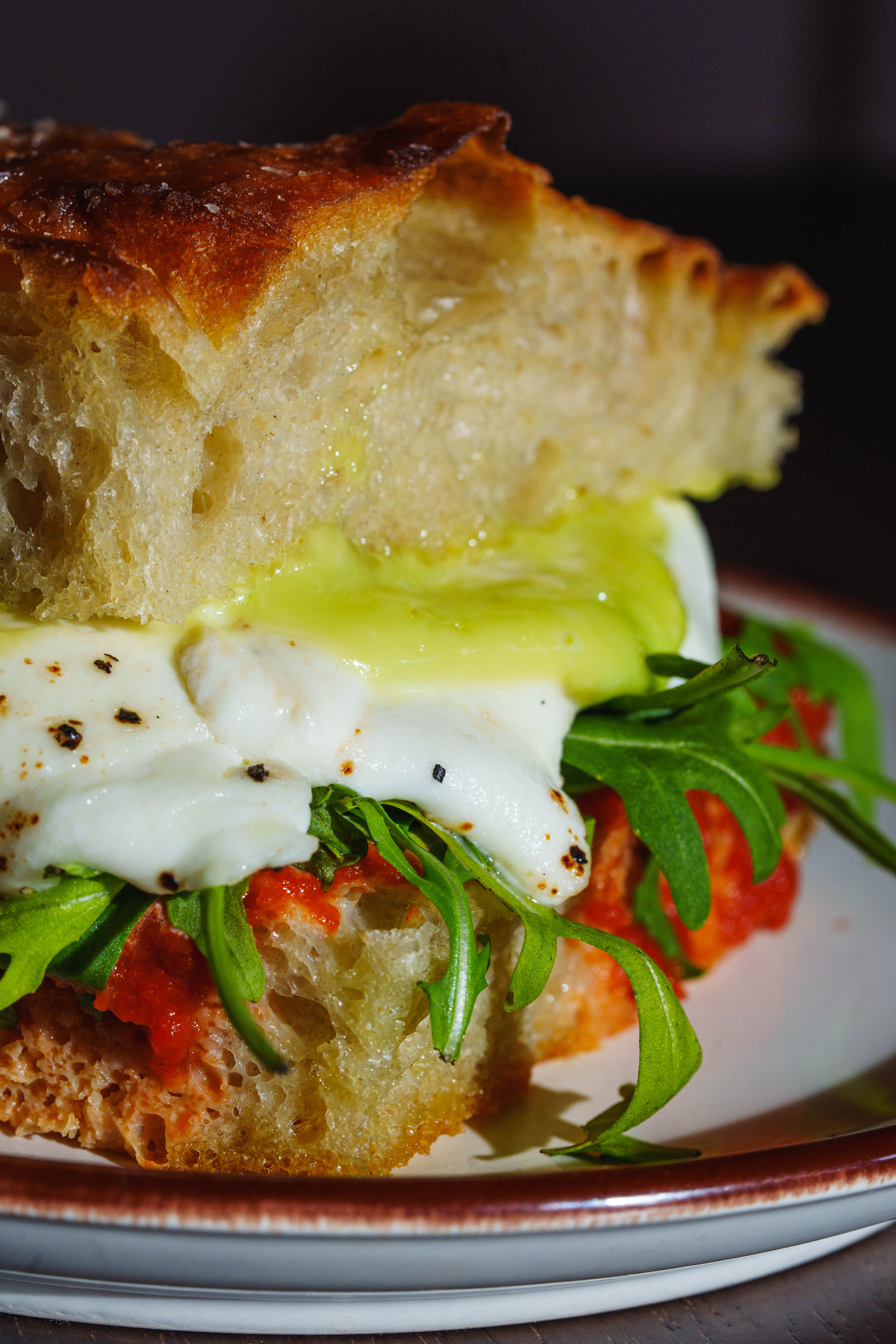 Focaccia sandwich with mozzarella, pesto, and arugula.