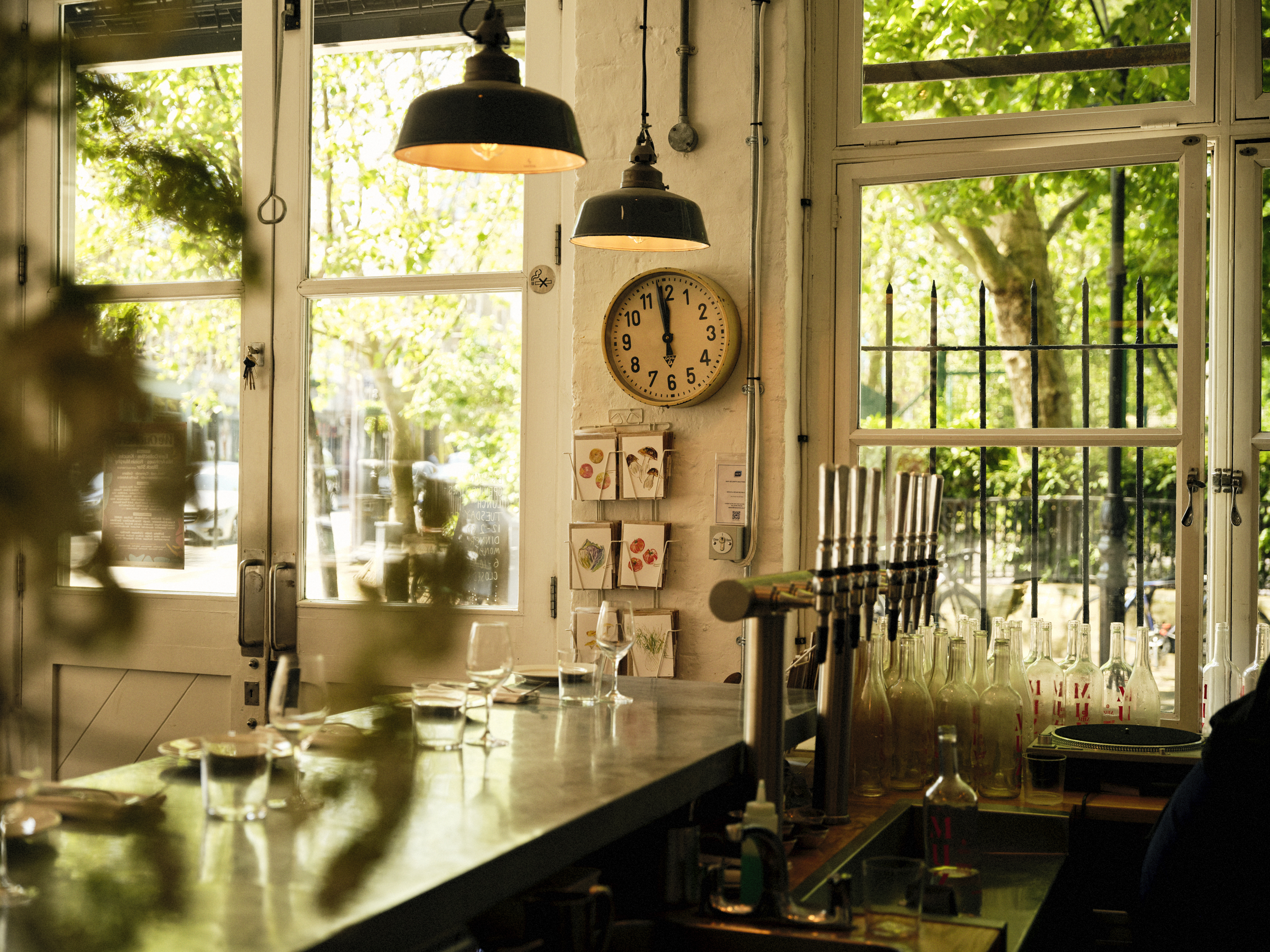 Interior view of Brawn restaurant, showing a bar with bottles, taps, and a clock on the wall.