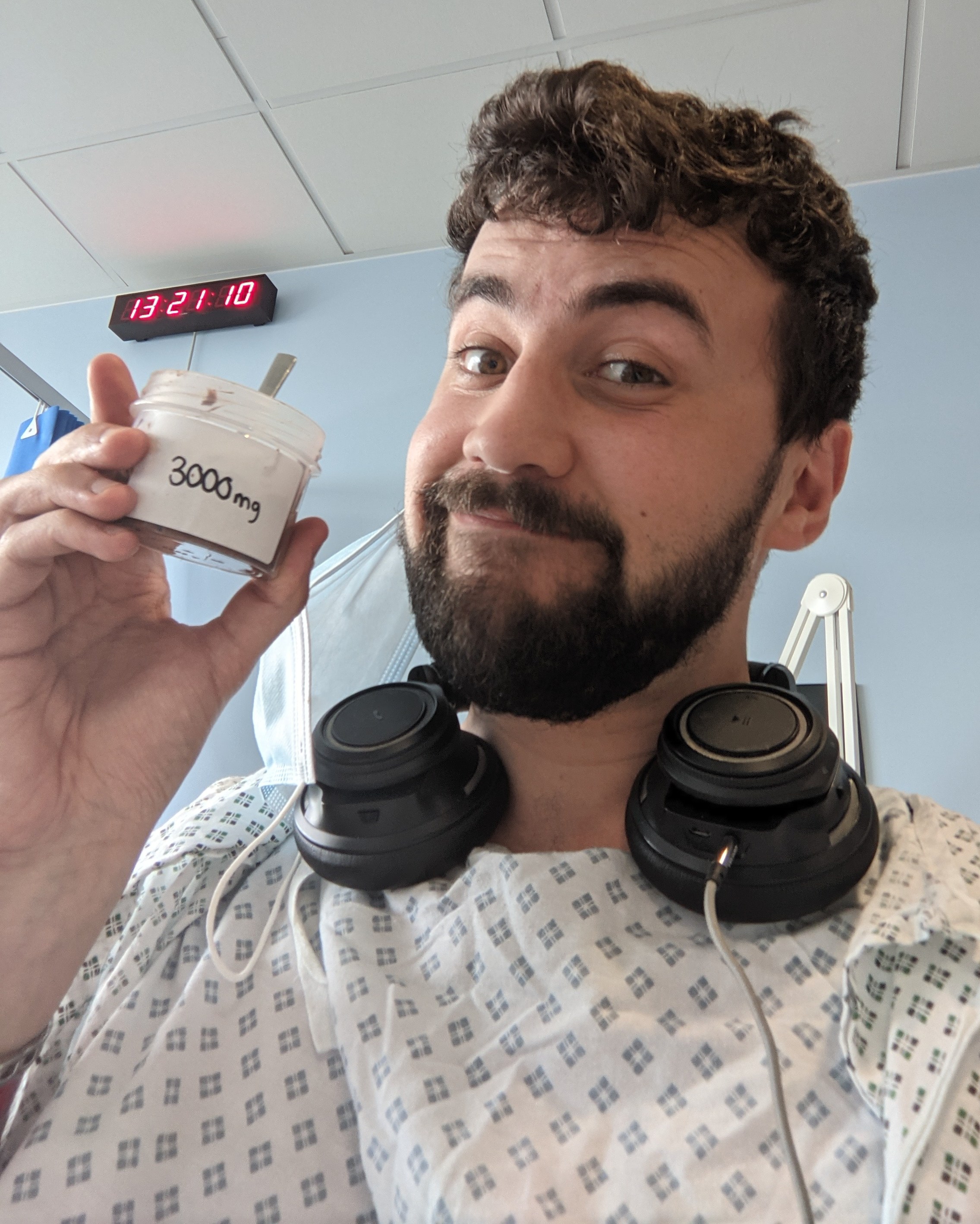A man in hospital attire holds a small container of peanut protein for his clinical trial.
