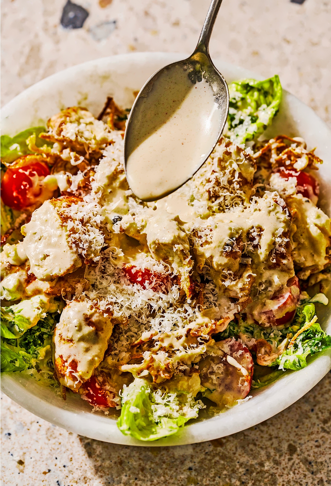 Caesar salad with dressing being poured over it.